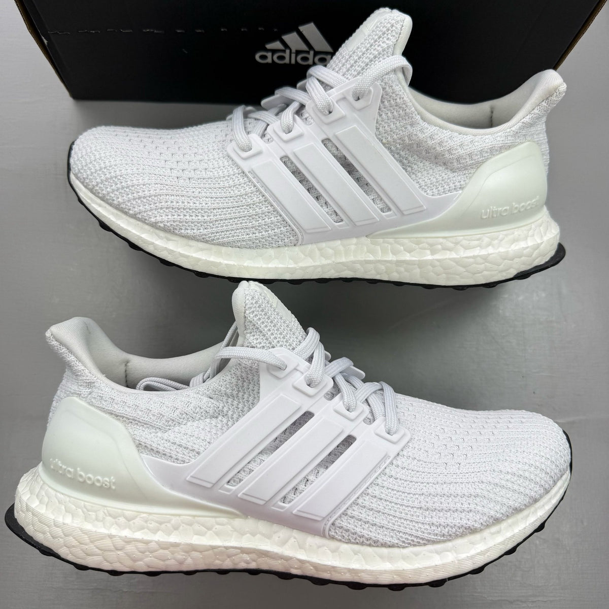 Adidas Ultra Boost 4.0 DNA white trainers with black accents and signature three-stripe logo.