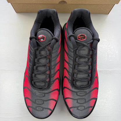 Nike black Air Max Plus TN trainers with reflective accents and red detailing.