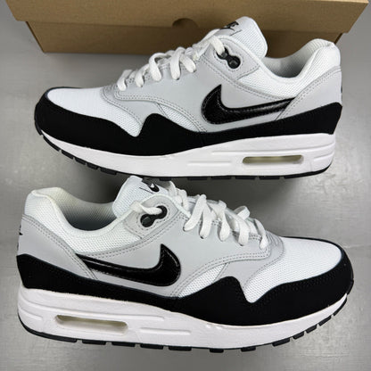 Nike Air Max 1 white trainers with black and grey accents, featuring logo details.