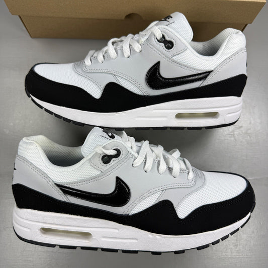 Nike Air Max 1 white trainers with black and grey accents, featuring logo details.