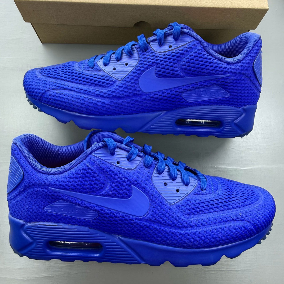Nike Air Max 90 blue trainers with breathable mesh upper and signature swoosh logo.
