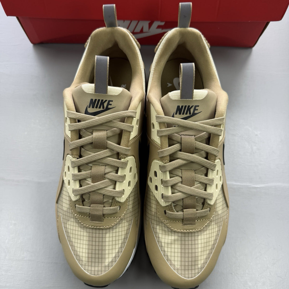 Nike Air Max 90 Drift beige trainers with black and brown accents, featuring logo detail.