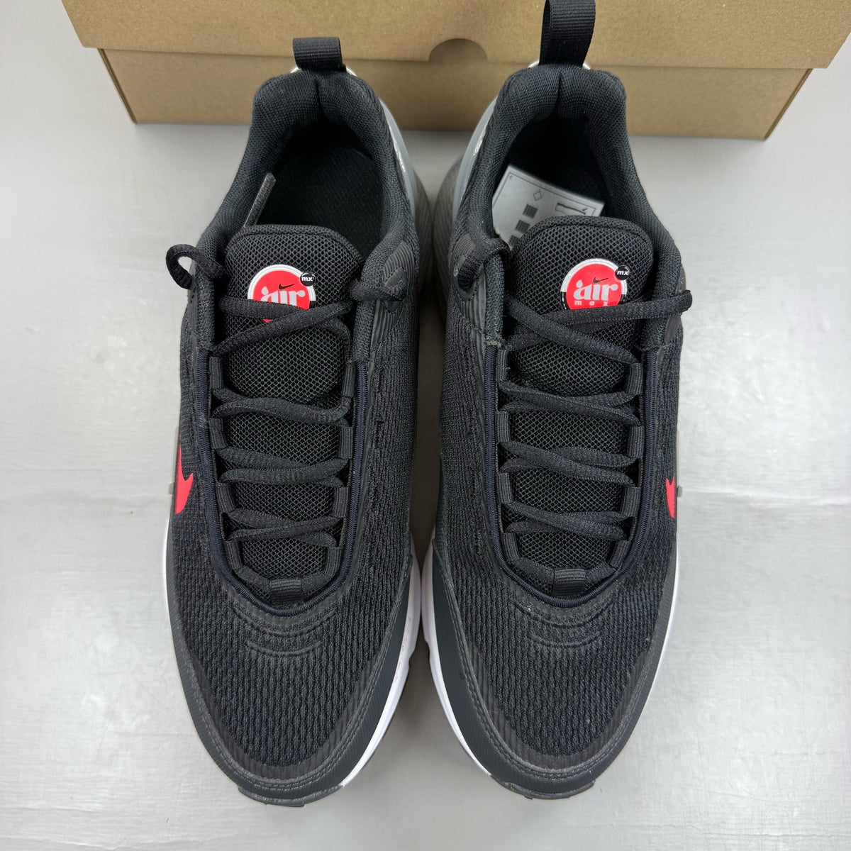 Nike black Air Max Pulse trainers with bright crimson accents and logo detail.