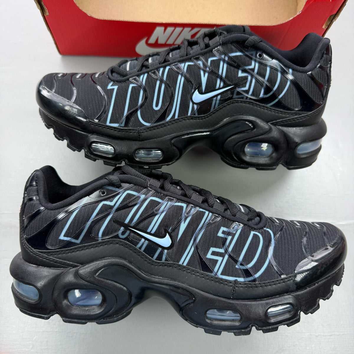 Nike Air Max Plus TN Tuned black trainers with grey accents and signature logo.