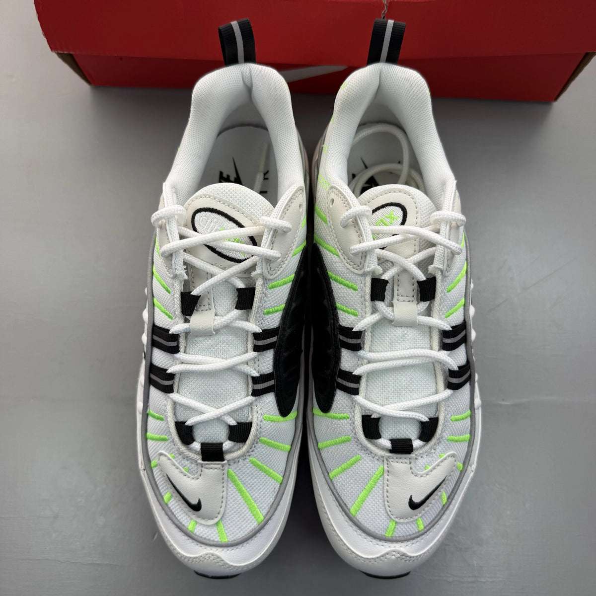 Nike Air Max 98 white trainers with electric green accents and mesh material.