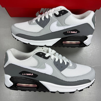 Nike Air Max 90 grey trainers with pink accents and white sole, featuring logo detail.