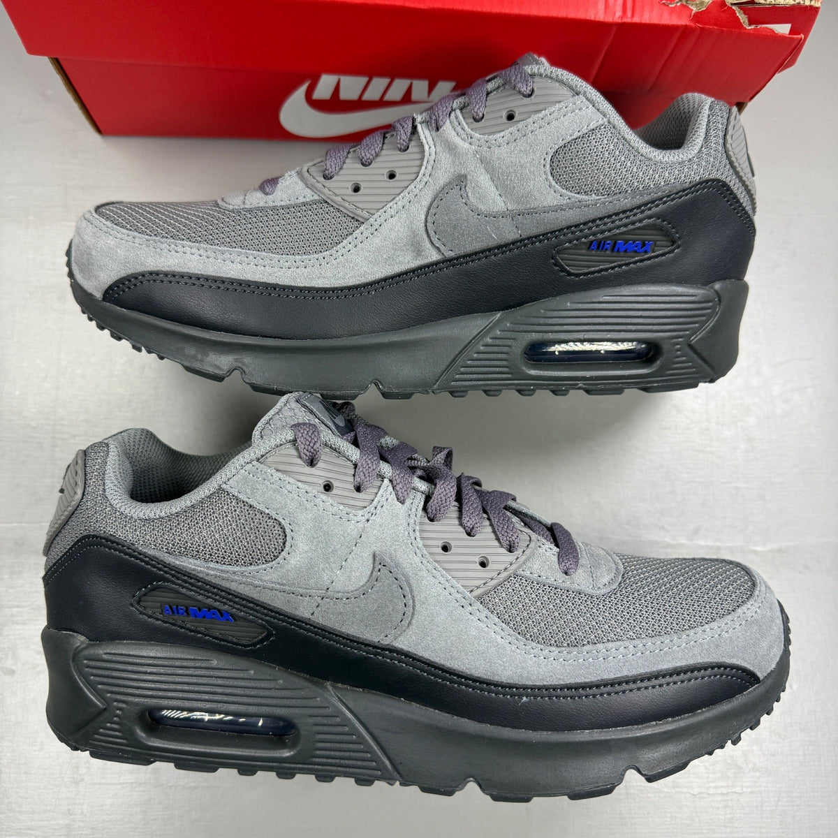 Nike Air Max 90 Tech grey trainers with blue accents and logo detail.