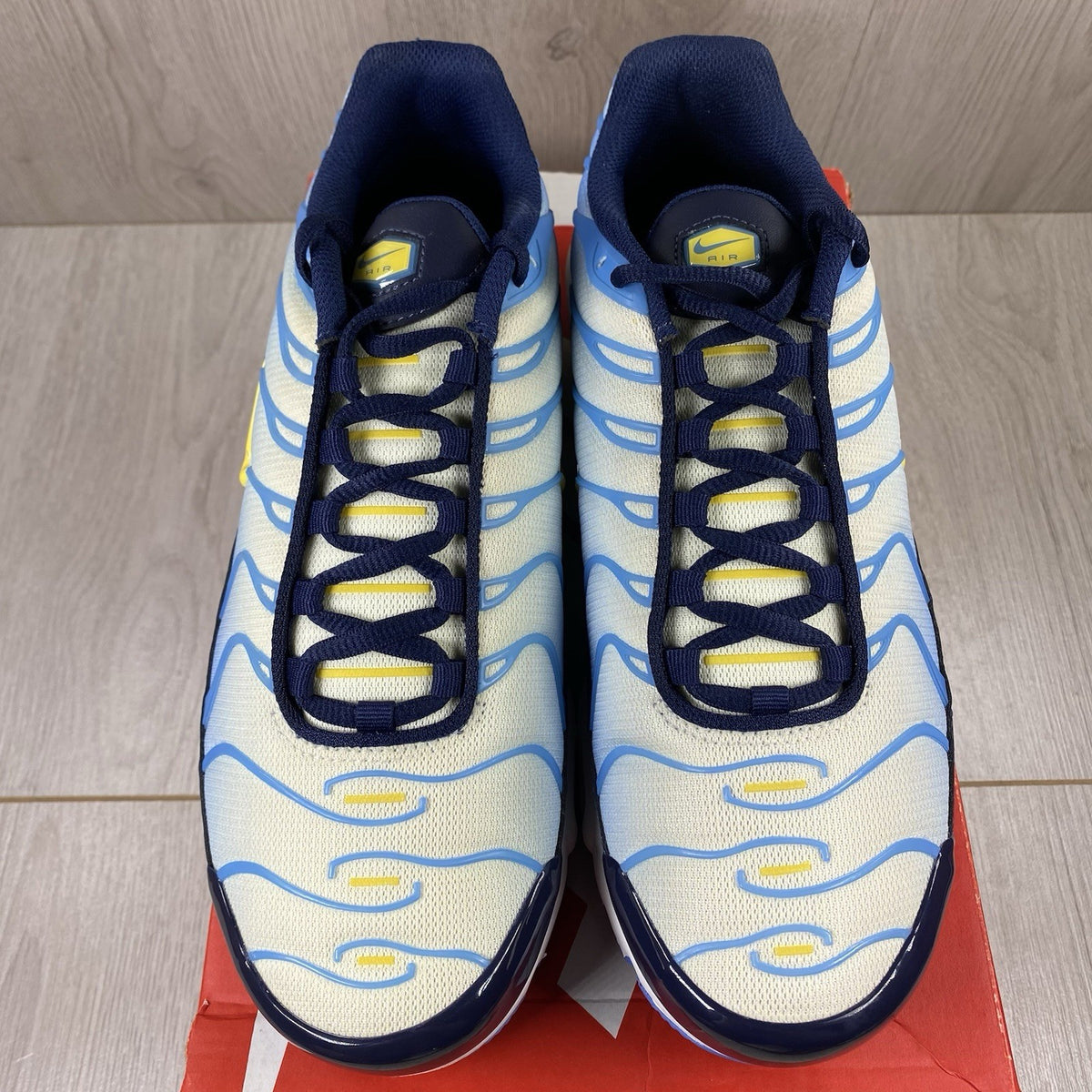 Nike Air Max Plus TN blue trainers with yellow accents and signature swoosh logo.
