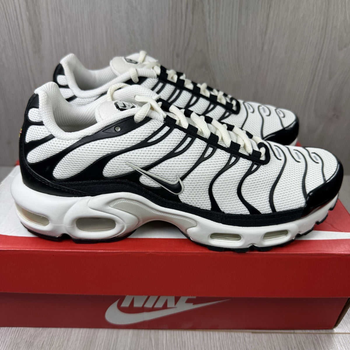 Nike Air Max Plus TN ESS trainers white with black accents and signature swoosh logo.