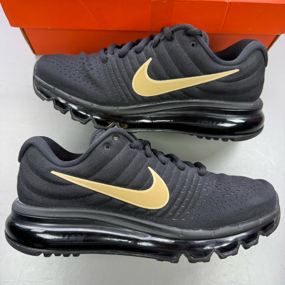 Nike Air Max 2017 GS trainers black with metallic gold accents and logo detail.