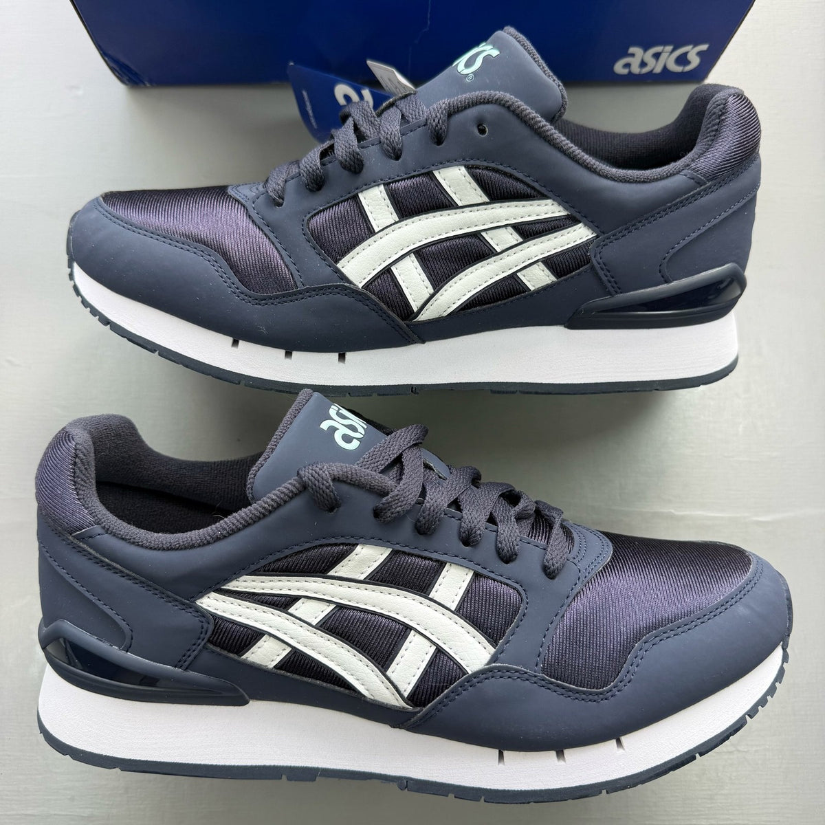 ASICS blue trainers with white accents and logo detail on the side.