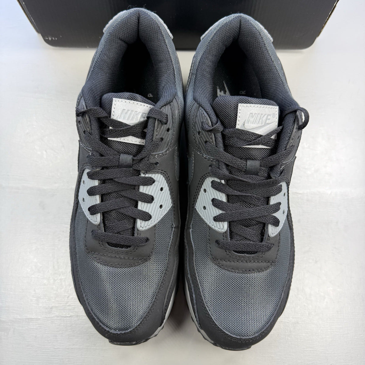 Nike Air Max 90 black trainers with anthracite and cool grey accents, iconic logo.