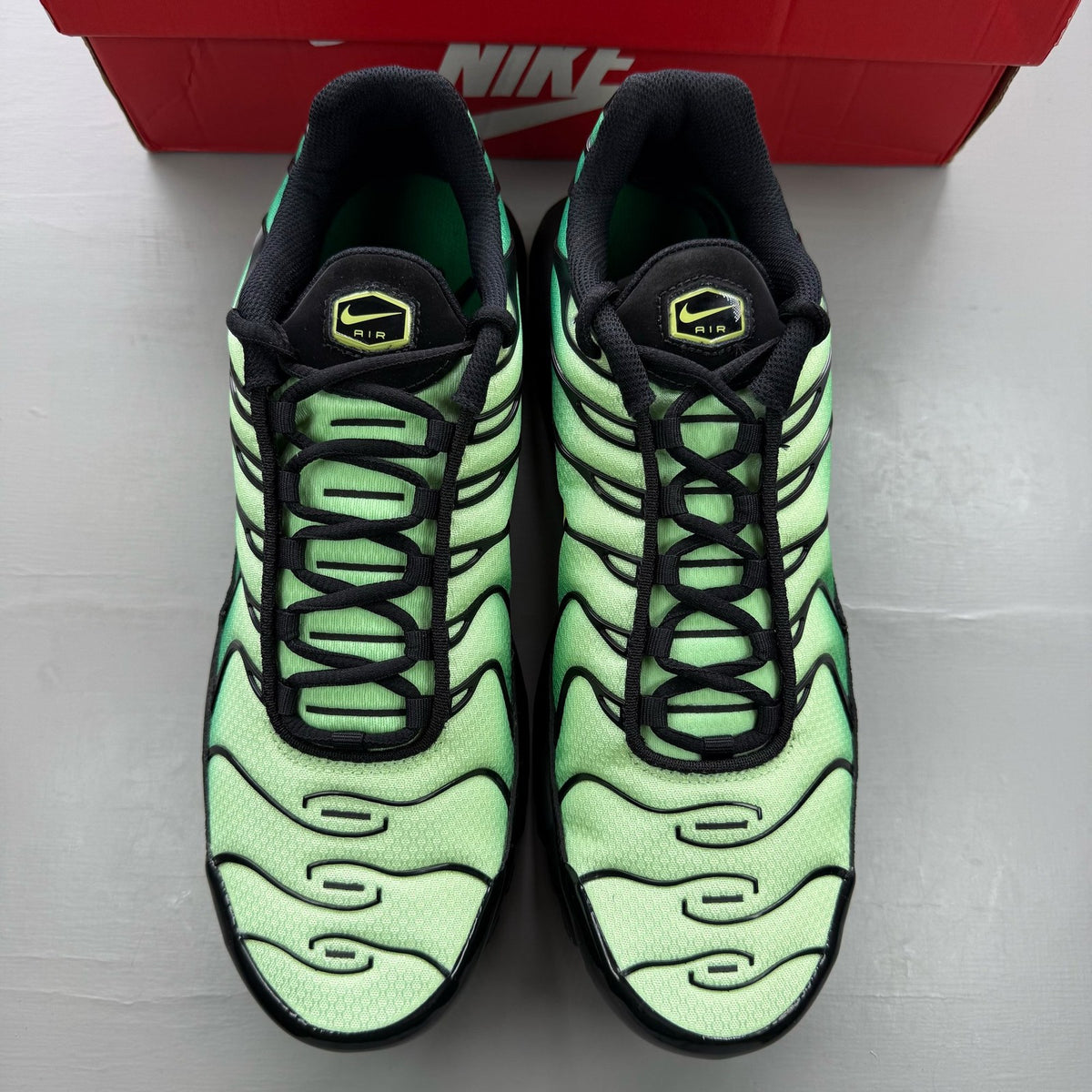 Nike Air Max Plus TN green trainers with lemon twist accents and signature logo.
