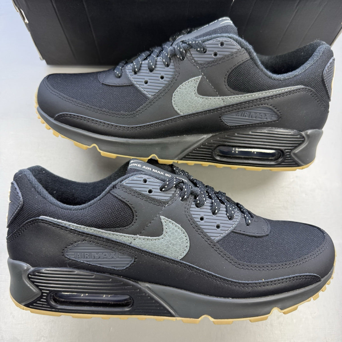 Nike Air Max 90 black trainers with reflective details and gum sole.