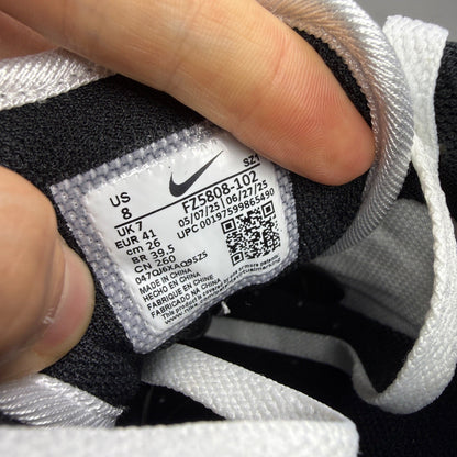 Nike Air Max 1 white trainers with pure platinum and black accents, classic logo detailing.