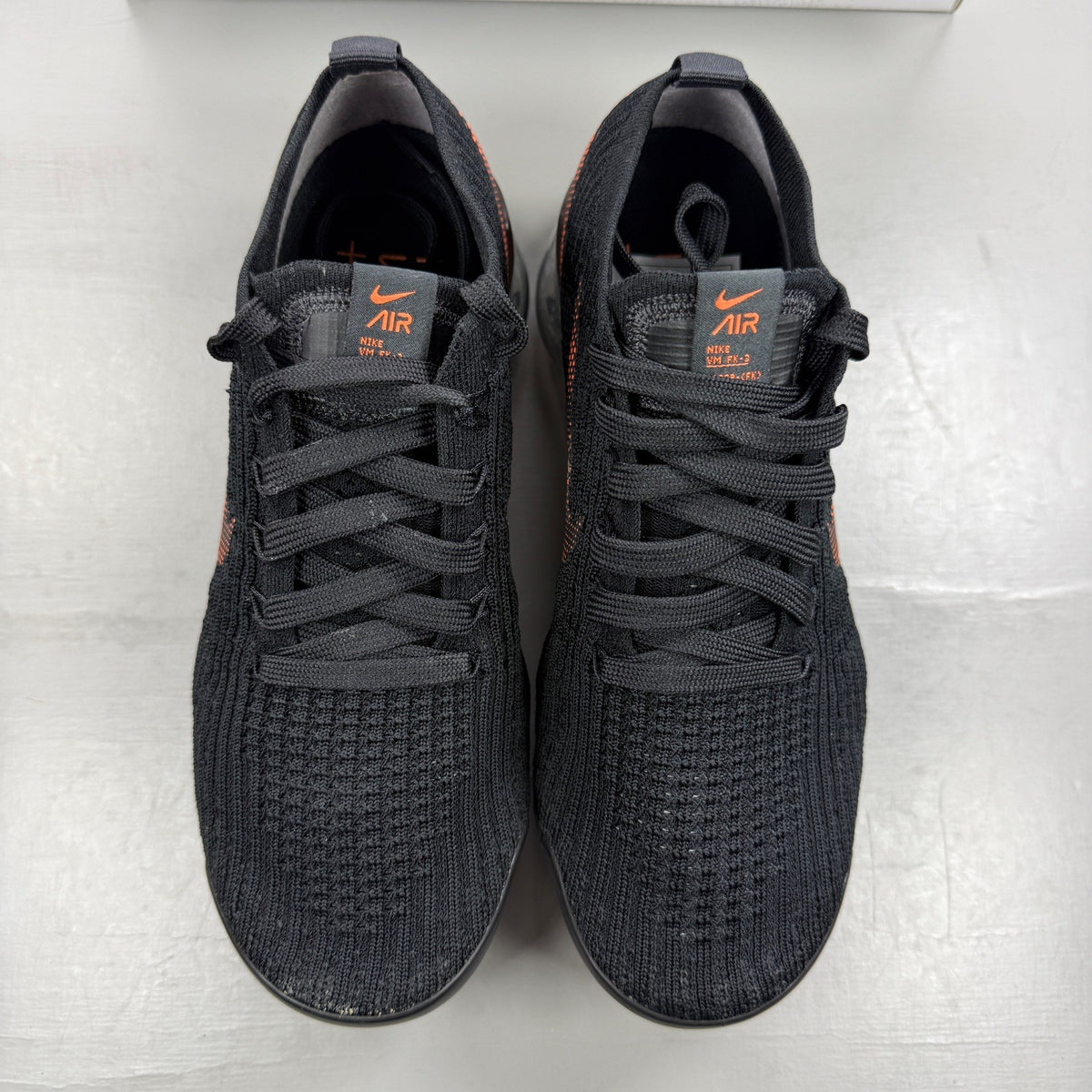 Nike Air VaporMax Flyknit 3 black trainers with total orange accents and breathable knit material.