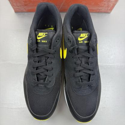 Nike Air Max 1 Essential black trainers with yellow accents and logo detail.