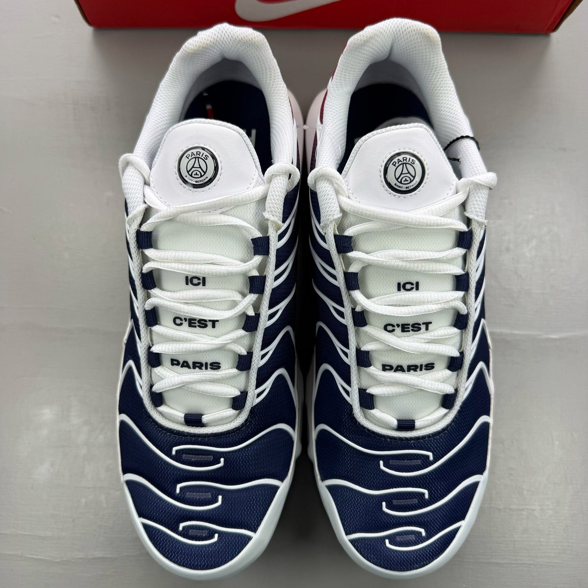 Nike Air Max Plus trainers white with navy and red accents, featuring logo details.