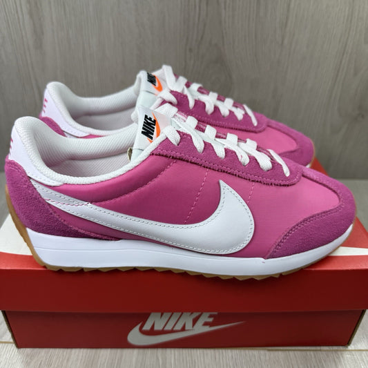 Nike white trainers with pink accents and gum sole, featuring iconic swoosh logo.