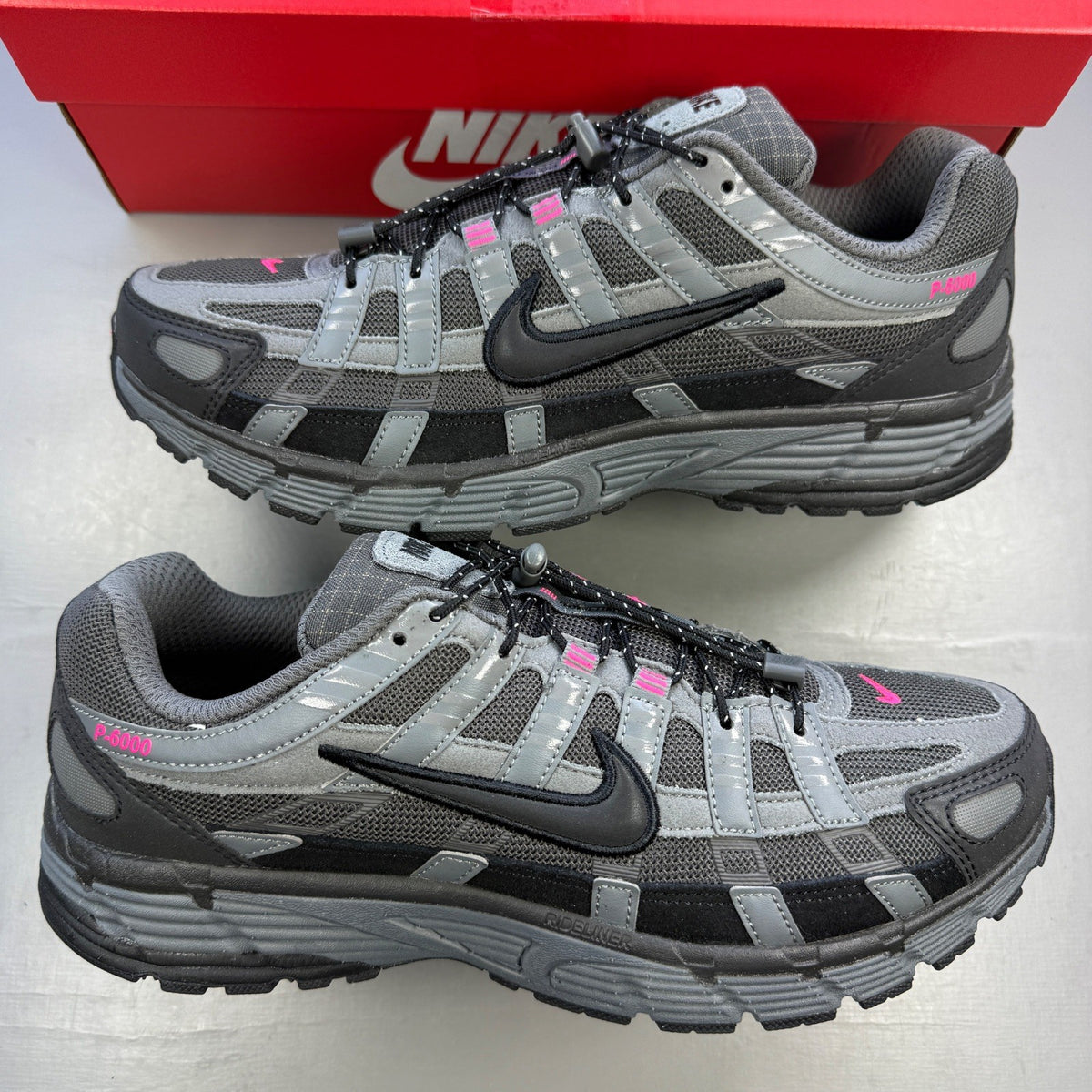 Nike P-6000 grey trainers with pink and black accents, mesh upper and logo detail.