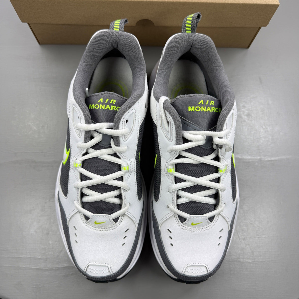 Nike Air Monarch IV white trainers with cool grey and green accents, featuring logo detail.