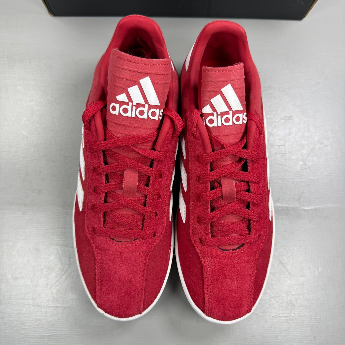 Adidas red suede running trainers with white logo and classic design details.
