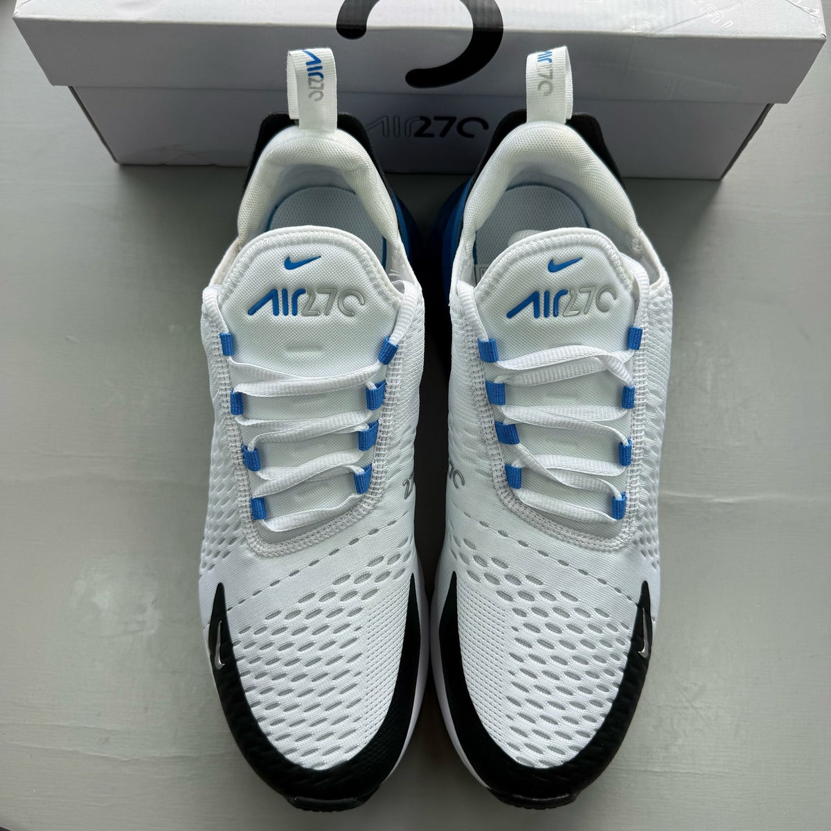 Nike Air Max 270 white trainers with laser blue accents and logo detail.