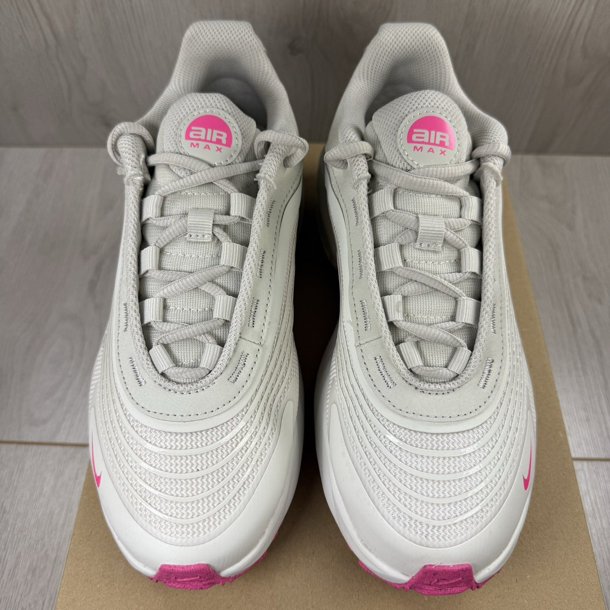 Nike Air Max trainers beige with pink accents and logo detail on the side.