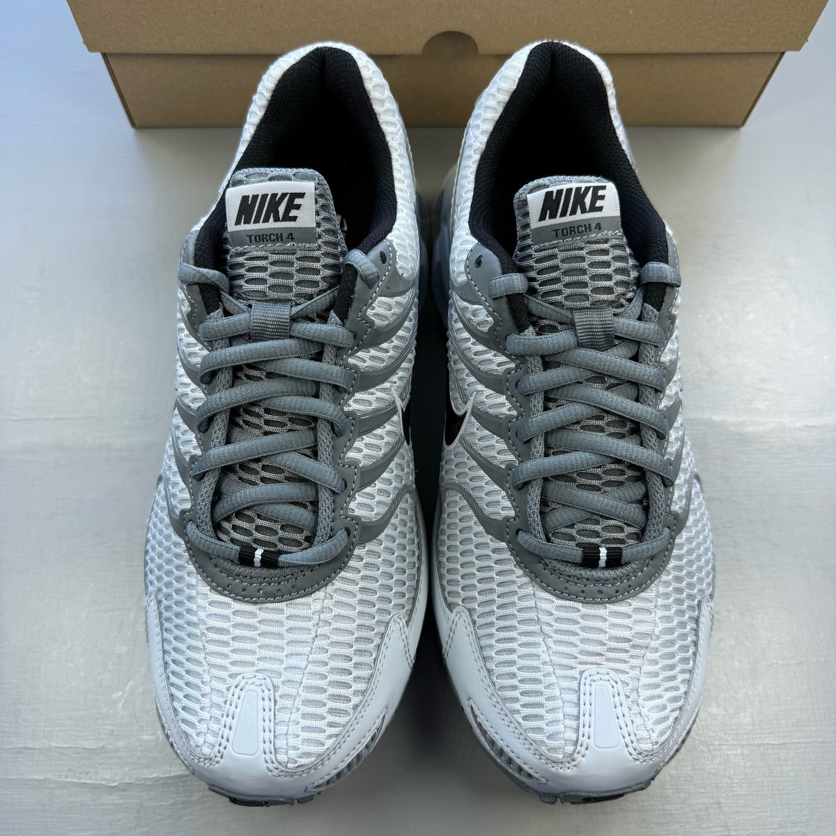 Nike Air Max Torch 4 grey and white trainers with mesh upper and signature swoosh logo.