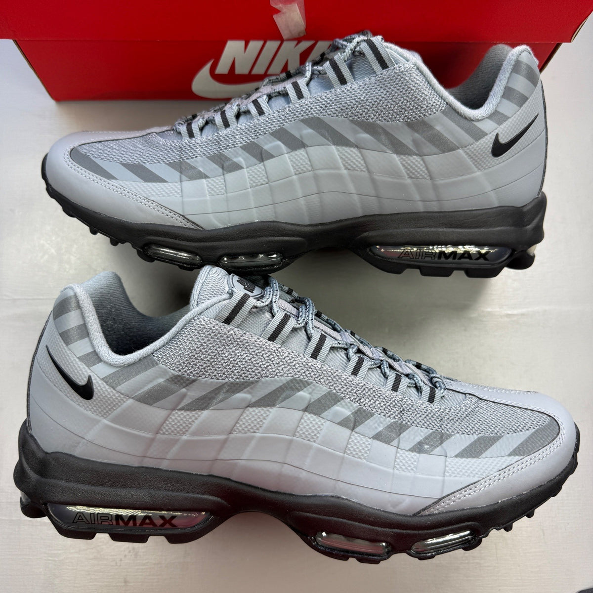 Nike Air Max 95 grey trainers with caution strip detailing and black accents.