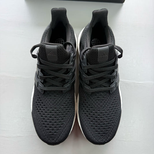 Adidas Ultraboost 1.0 black trainers with white accents and signature three-stripe logo.