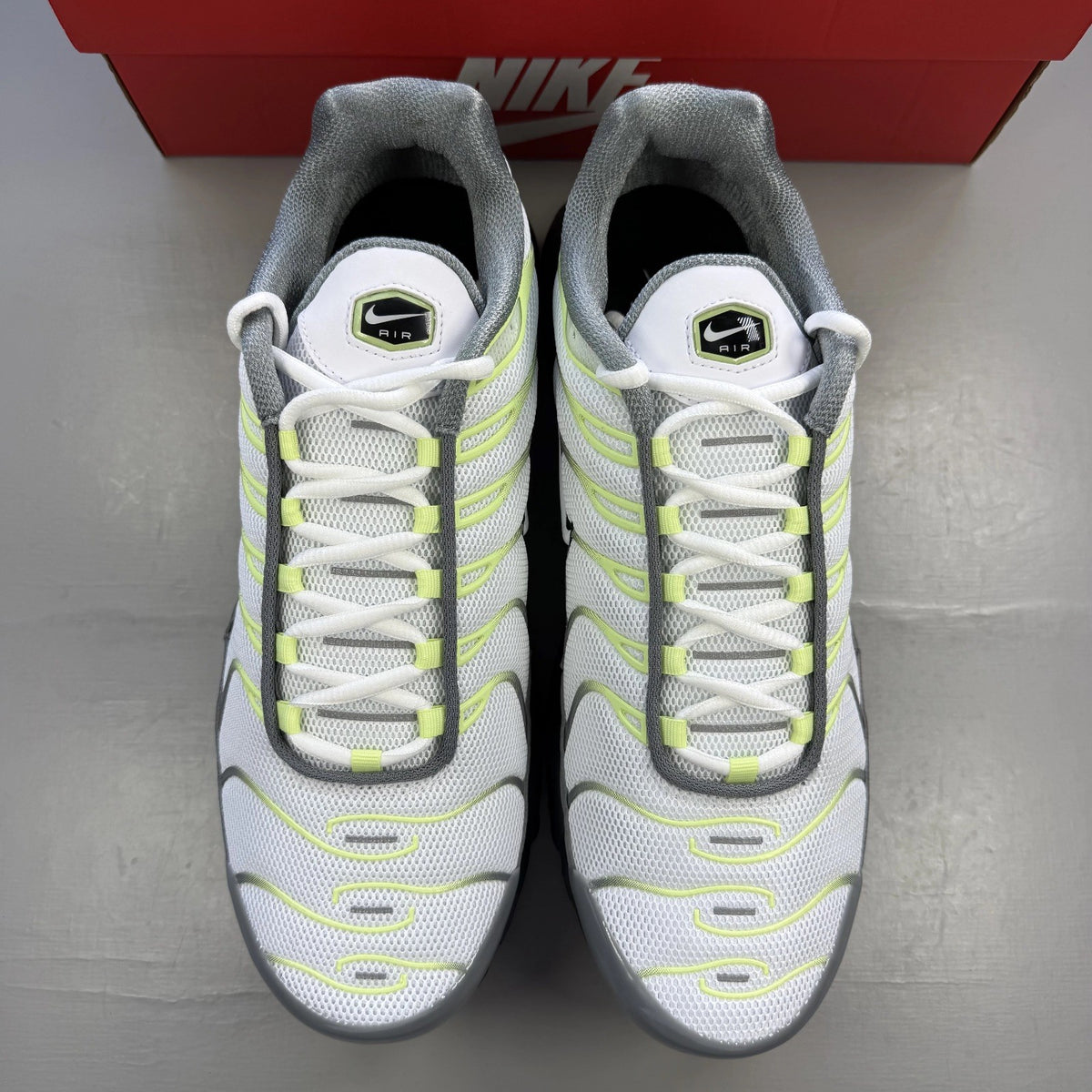 Nike Air Max Plus TN grey trainers with white and liquid lime accents, logo detail.
