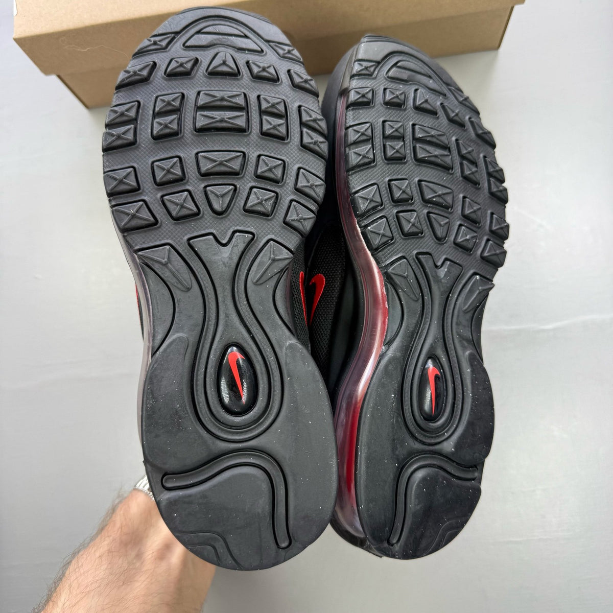 Nike Air Max 97 black trainers with red accents and signature logo details.