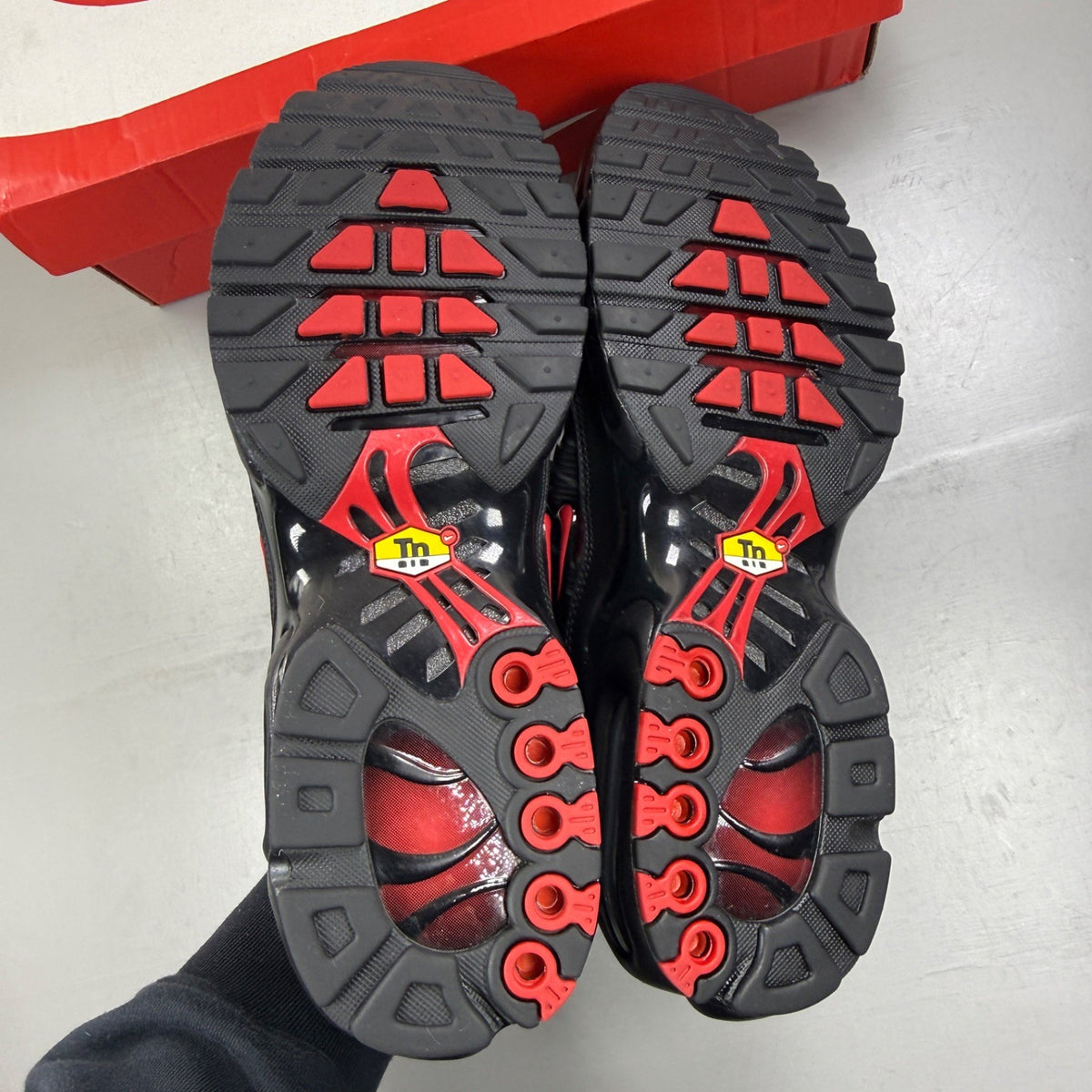 Nike Air Max Plus TN black trainers with red accents and iconic Tuned Air sole.
