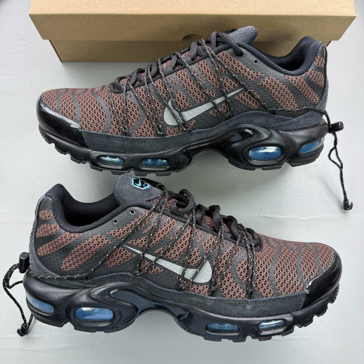 Nike Air Max Plus TN black trainers with distinctive wave pattern and cushioned sole.