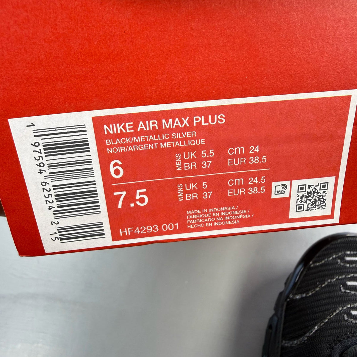 Nike Air Max Plus TN black trainers with university red accents and visible logo details.