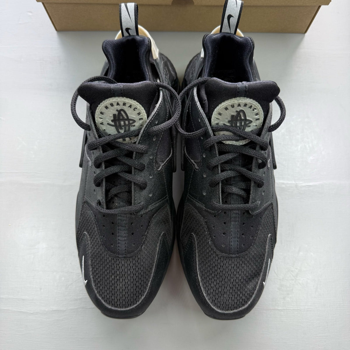 Nike black Air Huarache trainers with metallic silver mini swoosh logo.