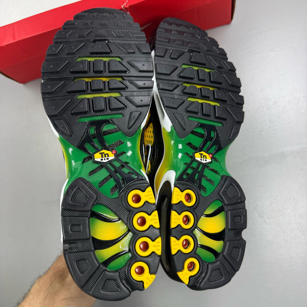 Nike Air Max Plus trainers yellow with pine green accents and logo detail.