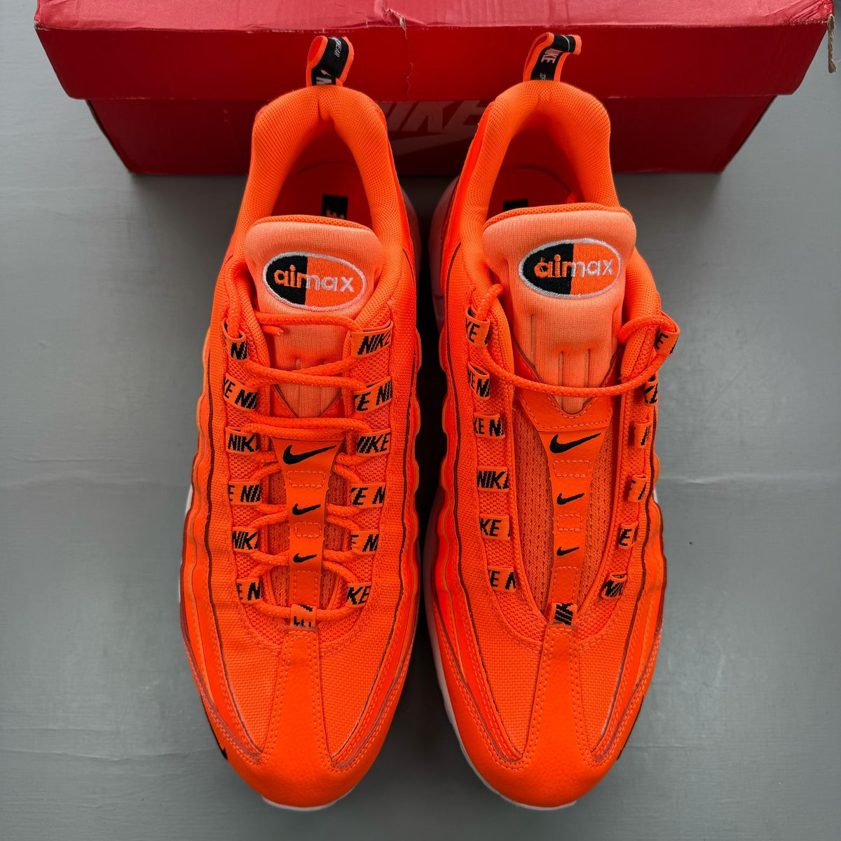 Nike Air Max 95 orange trainers with white overbranding and logo details.