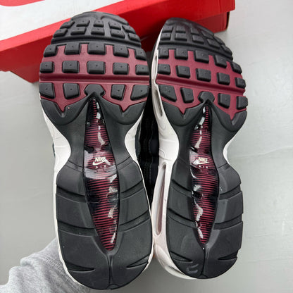 Nike black trainers with red accents and grey detailing, featuring iconic Air Max design.