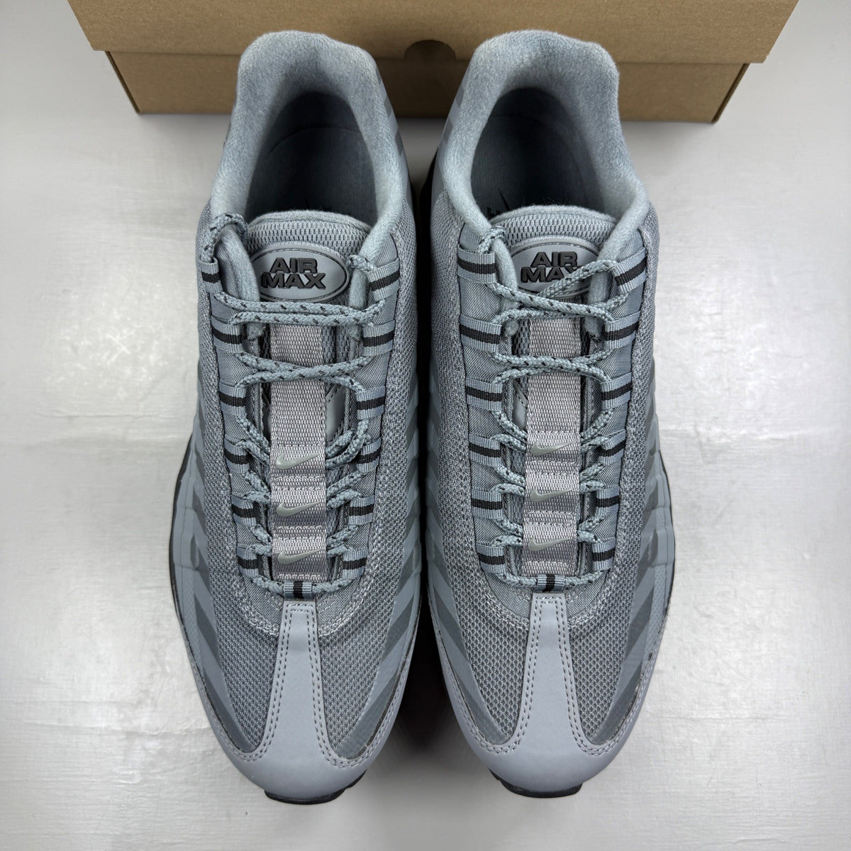 Nike Air Max 95 grey trainers with caution strip detailing and black accents.