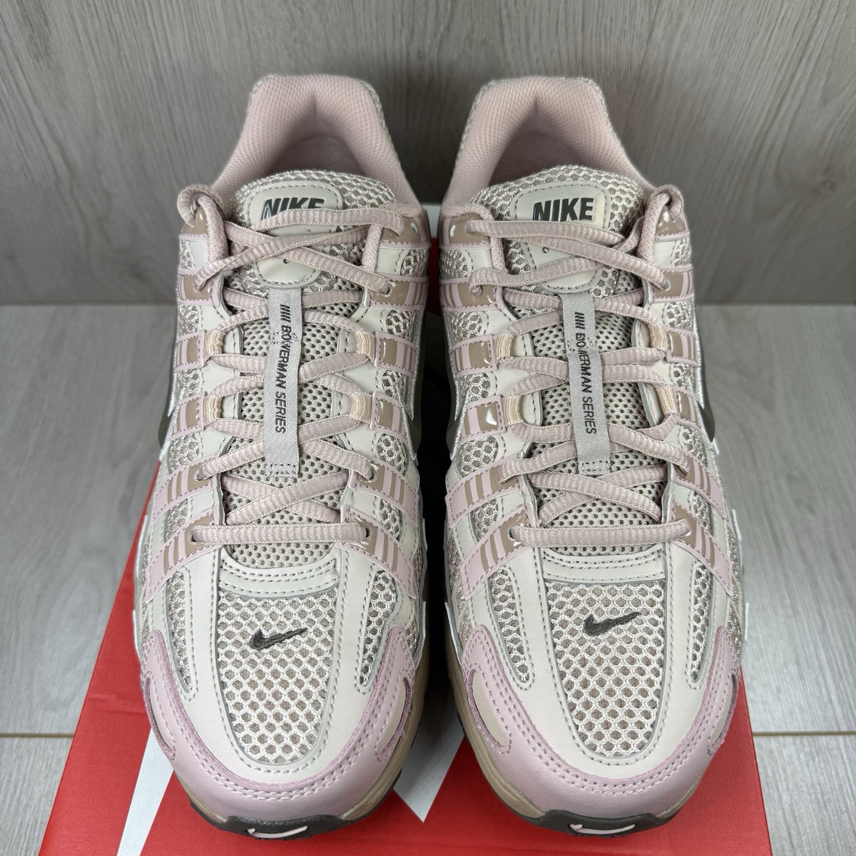 Nike beige trainers with pink accents and mesh detailing, featuring iconic swoosh logo.