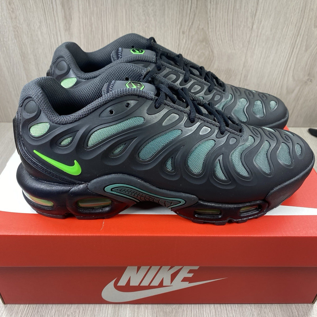 Nike Air Max Plus trainers black with volt green accents and signature swoosh logo.