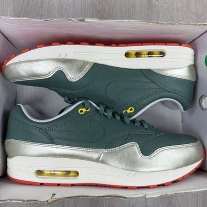 Nike Air Max 1 trainers green with white and silver accents, featuring iconic logo.