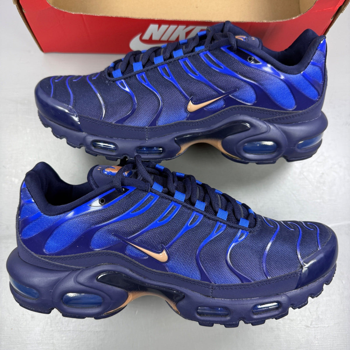 Nike running shoes metallic blue with copper accents and signature logo.