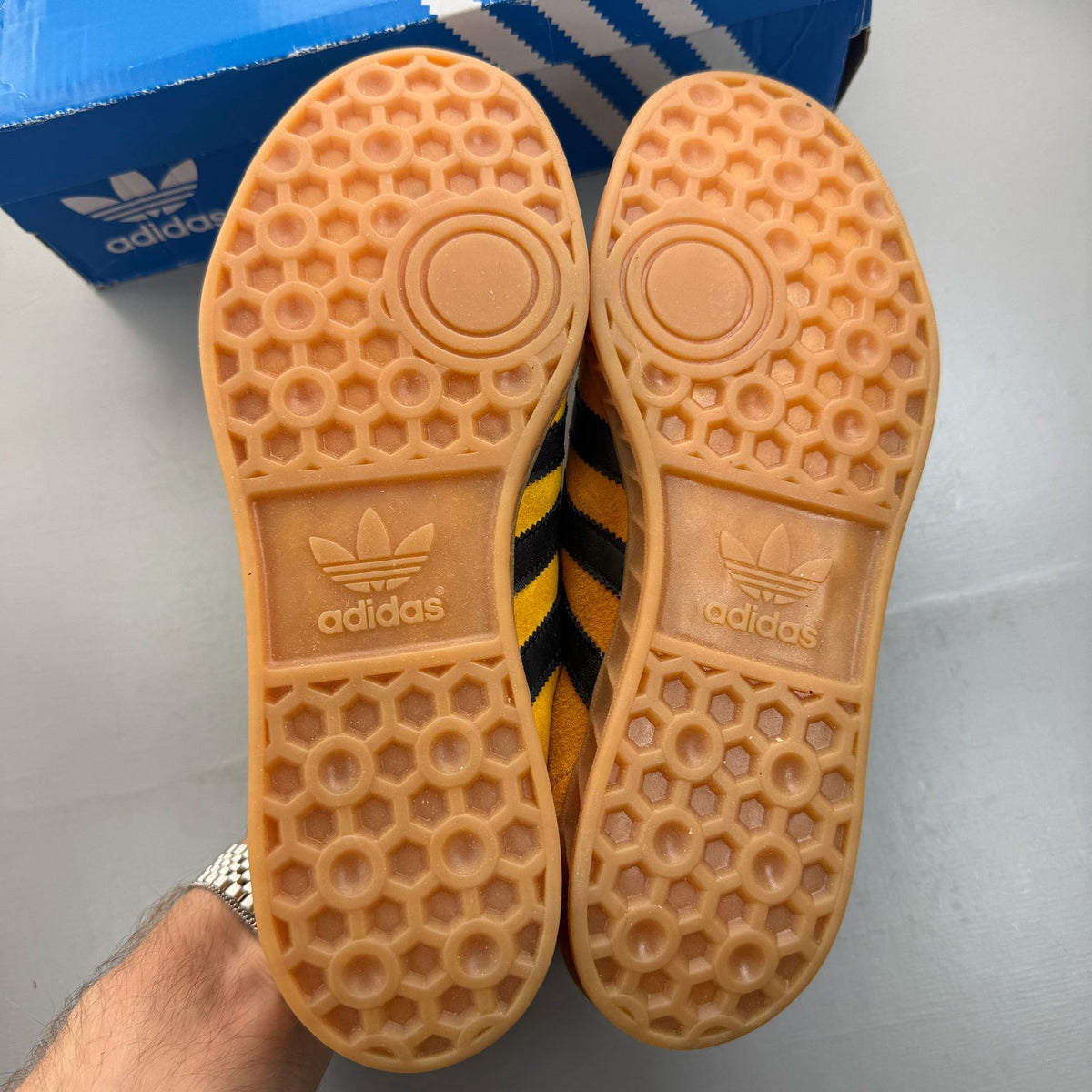 Adidas yellow trainers with black and gold accents, featuring iconic logo detail.