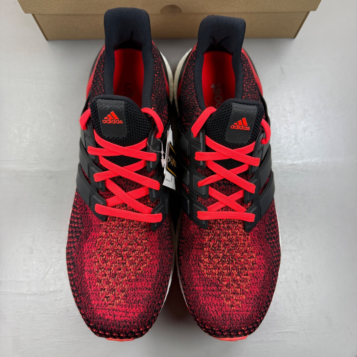 Adidas Ultra Boost 2.0 red trainers with black accents and signature three-stripe logo.