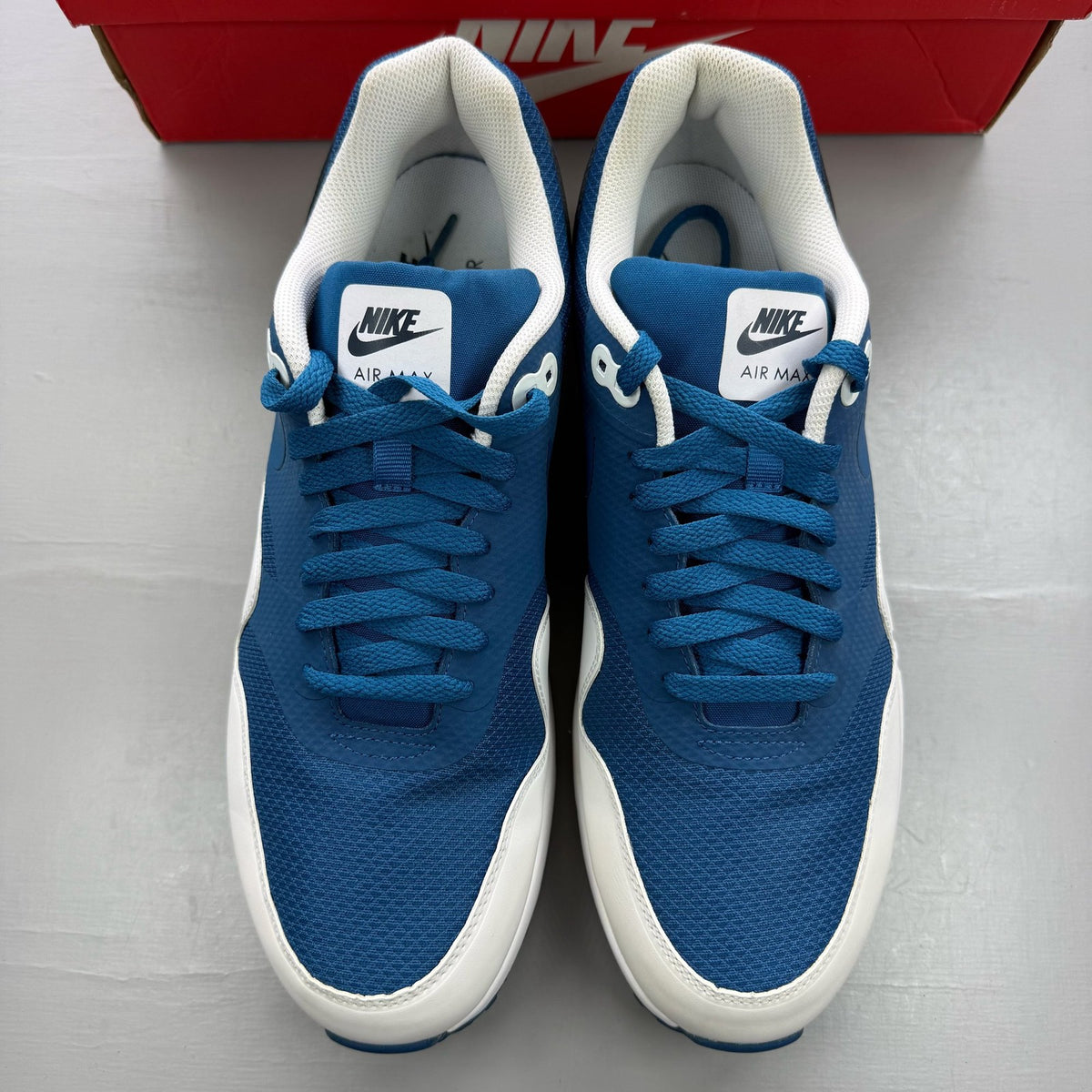 Nike Air Max 1 blue trainers with essential design and logo detail.