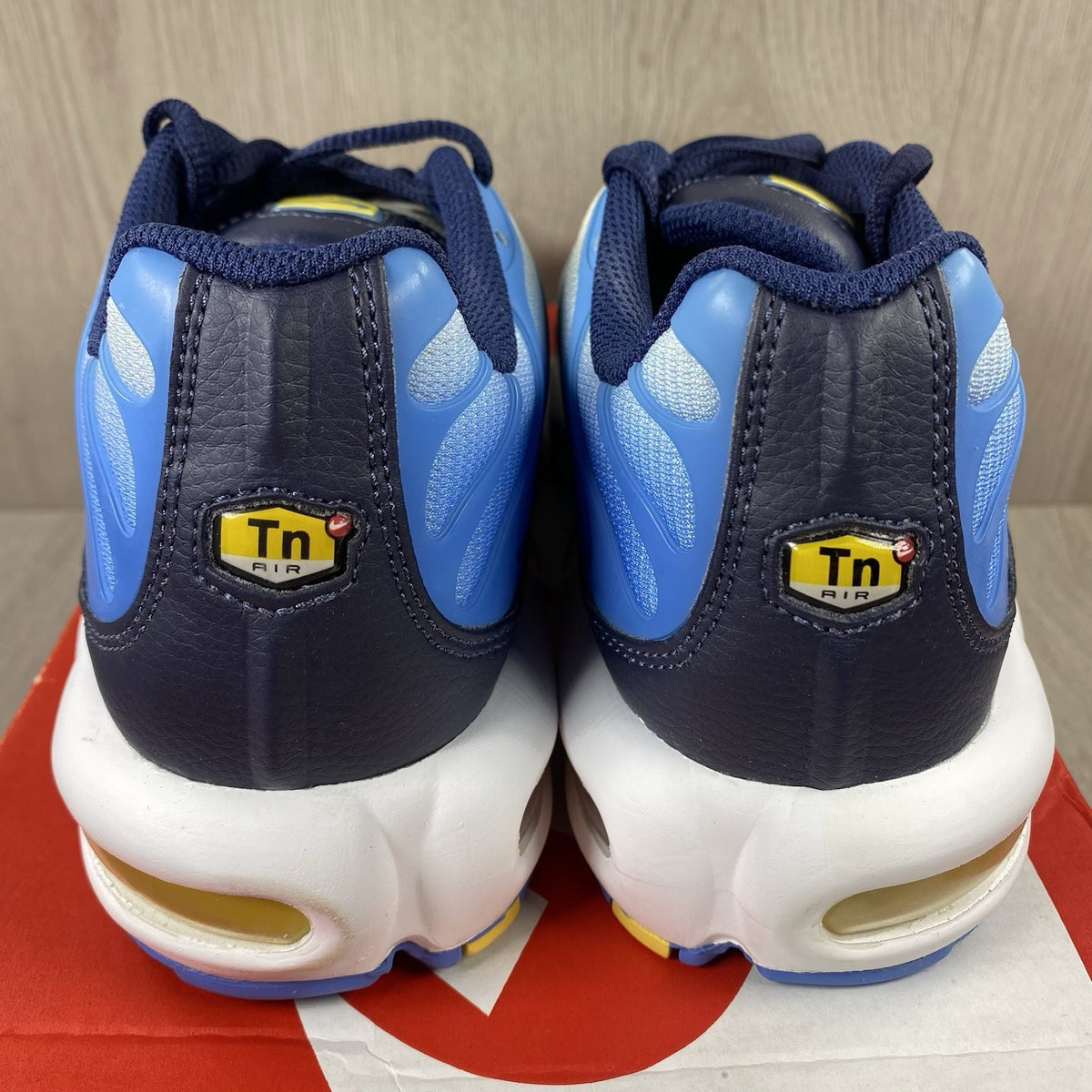 Nike Air Max Plus TN blue trainers with yellow accents and signature swoosh logo.