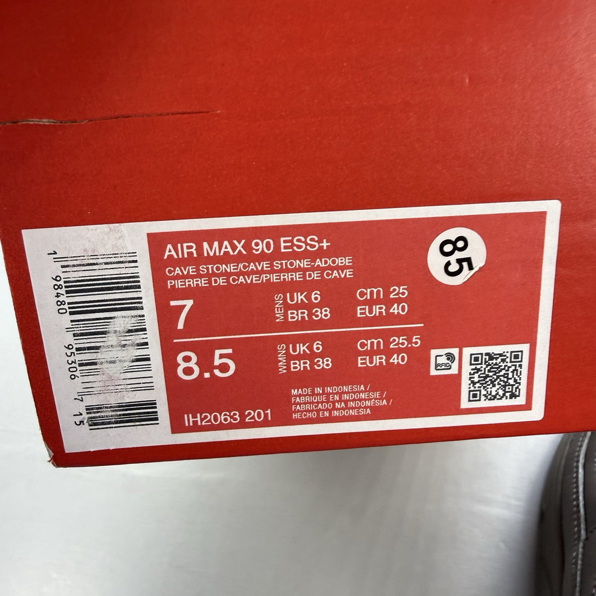 Nike Air Max 90 trainers grey with red accents and logo detail.